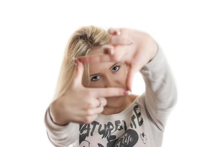 Young girl looking through her hands with the focus on the face isolated on whiteの写真素材