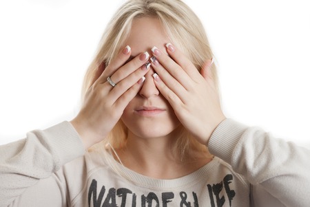 Beautifull young girl covering her face by her hands, isolated on whiteの写真素材