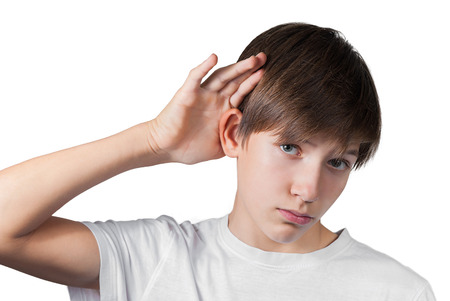 Boy hearing something enclosing his hand to his ear isolated on whiteの写真素材