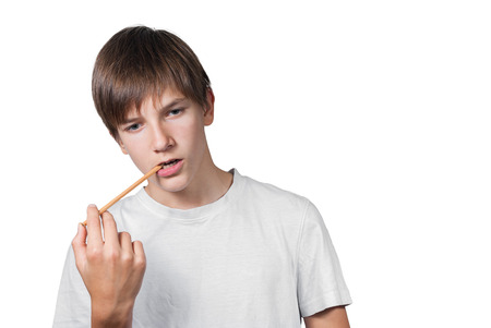 Schoolboy with a pencil in his mouth isolated on white backgroundの写真素材