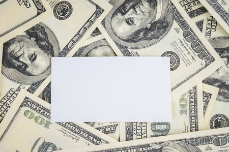 Visiting card laying on money background made of one hundred dollars notesの写真素材