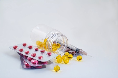 Pills in plastic bottle, tablets in packings and syringe on white backgroundの写真素材