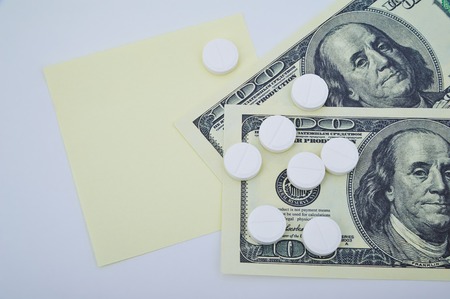 Tablets lying on two one hundred dollar bills and sticker