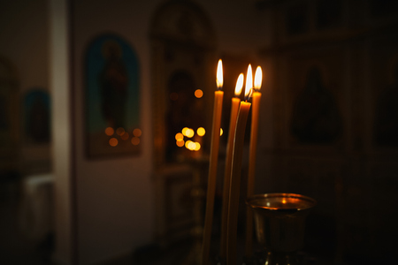 Photo of three burning candles in churchの写真素材