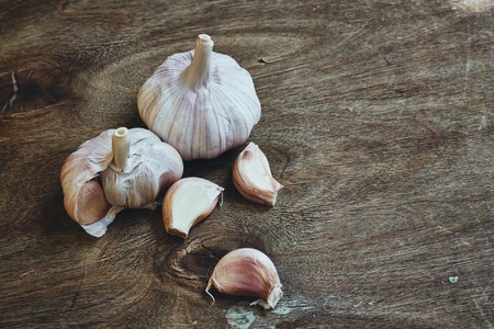 Photo of three garlic cloves on wooden cutting boardの写真素材