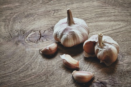 Frome above photo of part of the garlic head and three garlic cloves on wooden tableの写真素材
