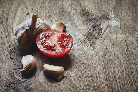 Photo of garlic bulb and cloves and the half of the red tomato on the blured backgroundの写真素材