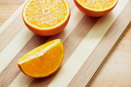 Two halves of orange and orange lobule on the wooden cutting boardの写真素材