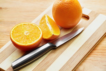 Knife and oranges on the wooden cutting board