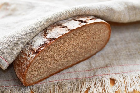 Sliced loaf of gray floured bread on cotton towel