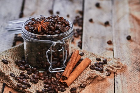 Coffee beans and star anise in jar with cinnamon on sackcloth on the wooden tableの写真素材
