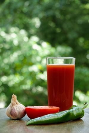 Composition  of fresh tomatoes, garlic, tomato juice, hot pepper and half of tomato on the wooden tableの写真素材