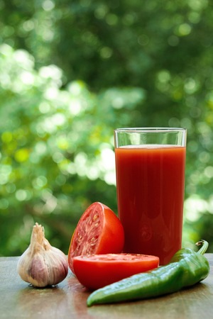 Composition  of fresh tomatoes, garlic, tomato juice, hot pepper and half of tomato on the wooden tableの写真素材