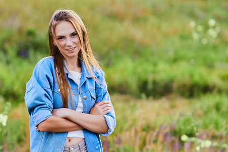 Happy young girl wearing blue jeans jacket in the fieldの写真素材