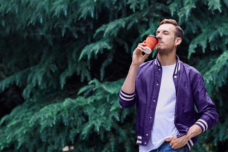 Man in the forest against green tree background with cup of coffeeの写真素材