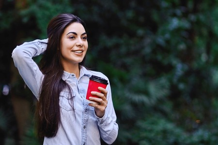 Young smiling woman holding the cup of coffeeの写真素材