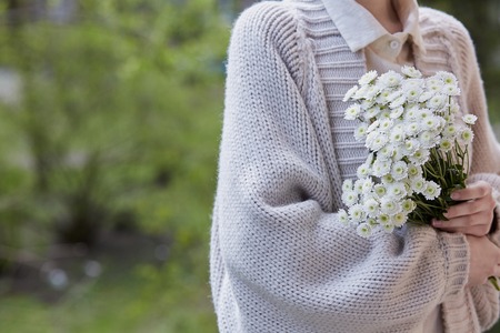 photo of young woman holding white flowers with green stem in her hands