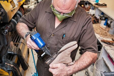 Shoemaker working on coronavirus days with mask