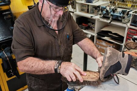 shoemaker man working in his shoe shop with mask