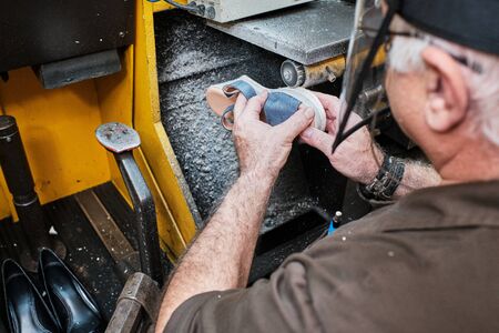 shoemaker man working in his shoe shop with maskの写真素材
