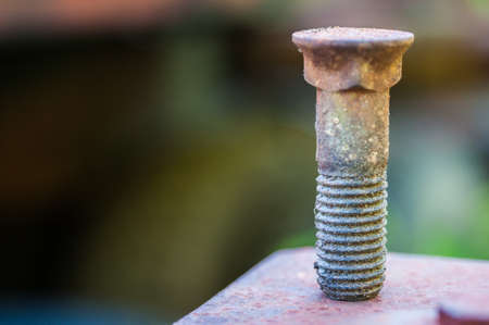 Rusty bolt on top of a red plate with shallow depht of fieldの写真素材