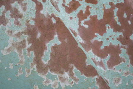 Detail of a rusty green car abandoned by the side of the road