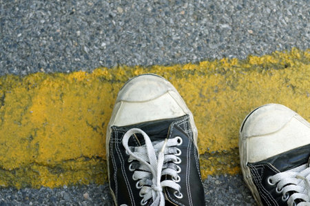 A black sneakers on the road with yellow line on the road, for concept background and texture.の写真素材