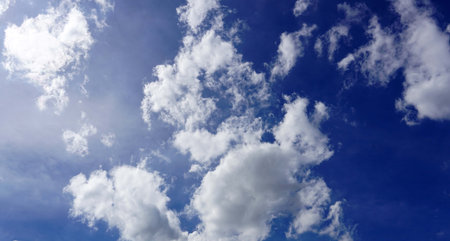 A blue sky background with cumulus white clouds in the sky then soft sun flare light.の写真素材