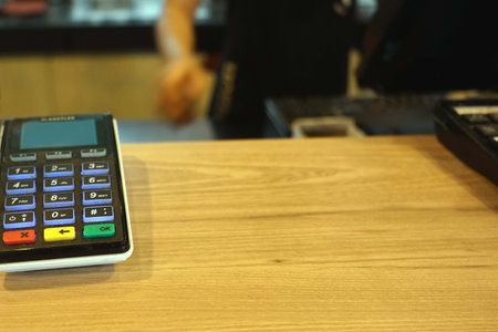 Payment terminal and credit card on the wooden table in coffee shop