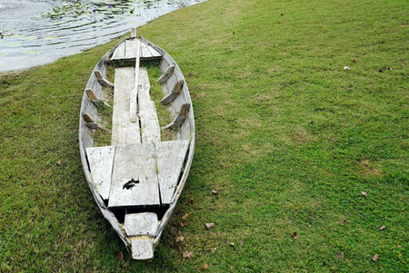 A old vintage wooden boat on the green grass beside a pond  in the park, vinatge classic stlye.の写真素材