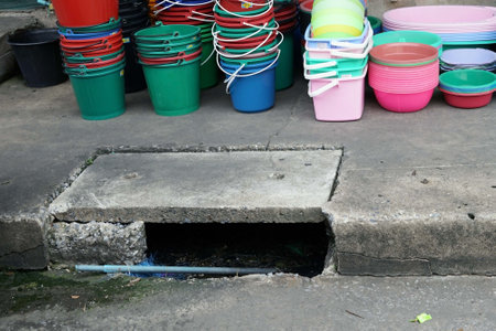 A plastic bucket and plastic cup on the concrete floor near a streest for sale.