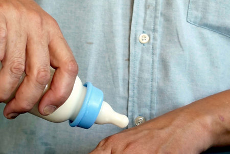 Close up of a hand of man using a milk bottle to testing a hot after mixing to a baby to drinking.の写真素材