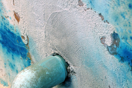 Closeup of old blue paint on a cement wall with a green pvc pipe water, abstract background.の写真素材