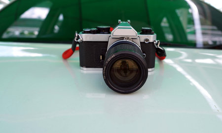 A retro film camera with red strap isolated on a front body car backside a car glass.の写真素材