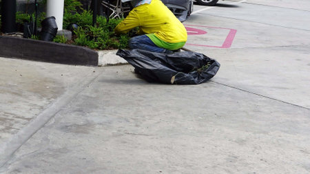 A worker was  gardening with planting trees on the floor with a garbage bag in the garden.の写真素材