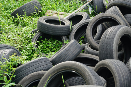 An old car tires stacked on the grass in a pile in area a car workshop, disposal recycling concepts.の写真素材