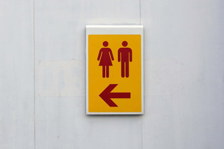 A yellow male and female toilet sign on the white wall.の写真素材