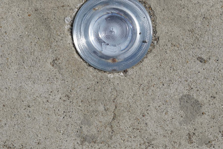 Close up a lamp mounted in the cement ground on the street.の写真素材