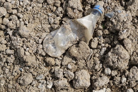 A plastic glass waste on pile of soil for planting trees, pollution of the environment.の写真素材