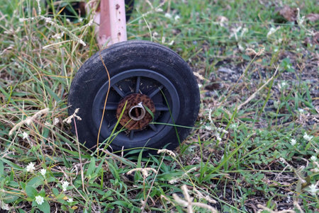 Close up a old black wheel of a barrier traffic in the field grass park.