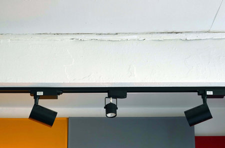 A ceiling light on the white wall with black lamp.