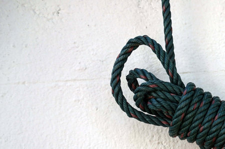 Rope tied to a white wall in a shipyard, closeup of photoの写真素材