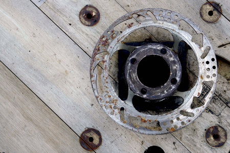 Close-up of old car brake disc lying on a wooden floorの写真素材