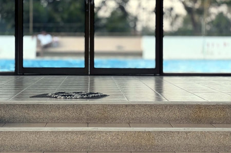 Swimming pool with wet tile floor and swimming pool in background.の写真素材