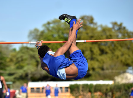 Young athletic boy competing in the high jump during a track and field meet