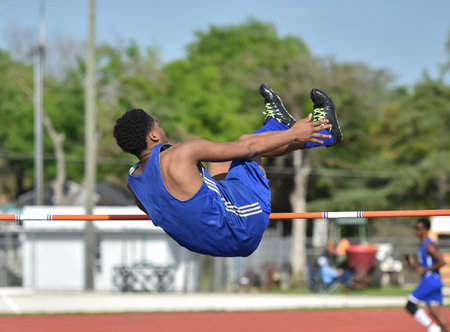 Young athletic boy competing in the high jump during a track and field meet