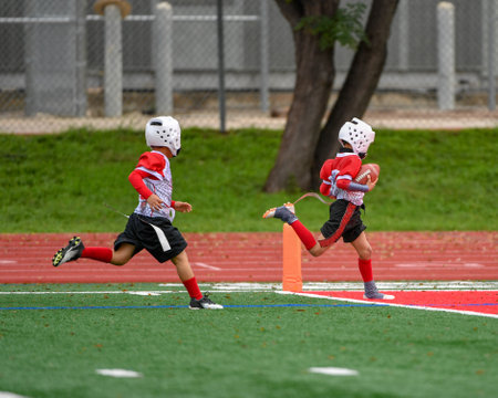 Young athletic boy catching, running and throwing the ball in a football gameの写真素材