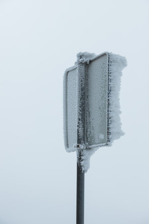 Isolated frozen traffic sign on a foggy morning. Vertical traffic sign frozen by adverse weather conditionsの写真素材