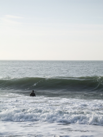 Photo taken at Baker Beach of the Presidio of San Francisco looking west to the open ocean where a surfer watching a wave come at himの写真素材