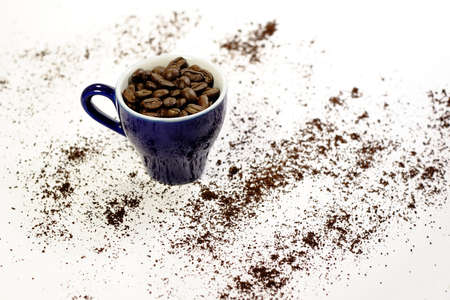 Cup with coffee beans with ground coffee in backgroundの写真素材